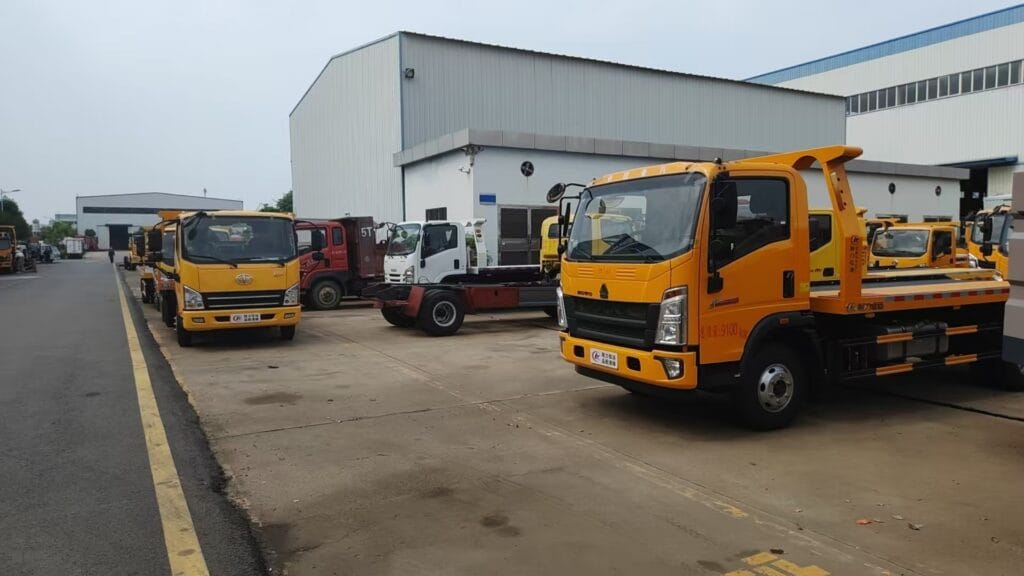 Multiple Rollback Tow Trucks Parked in Factory Yard Left Side View