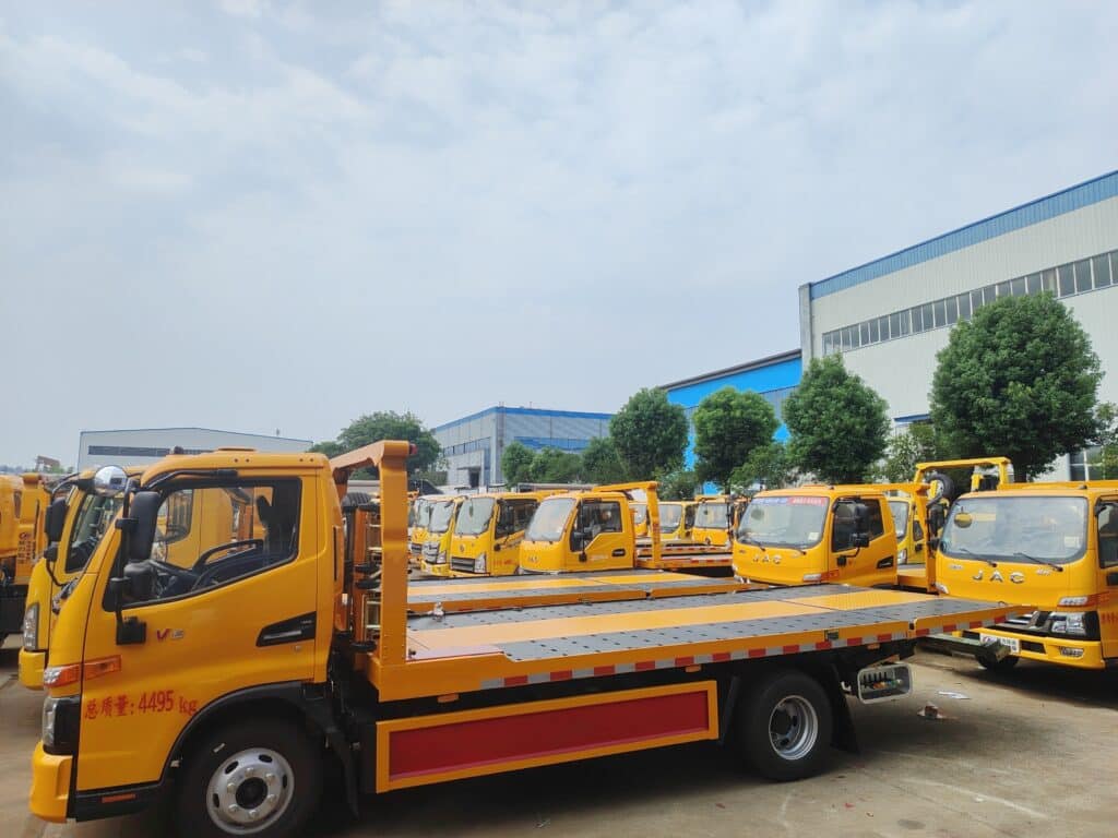 Multiple Rollback Tow Trucks Parked in Factory Yard Side View